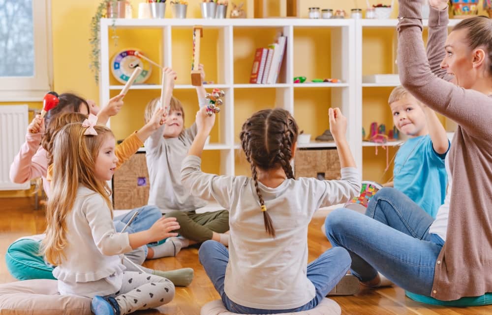 Kindergarten teacher and students holding musical instruments in class.